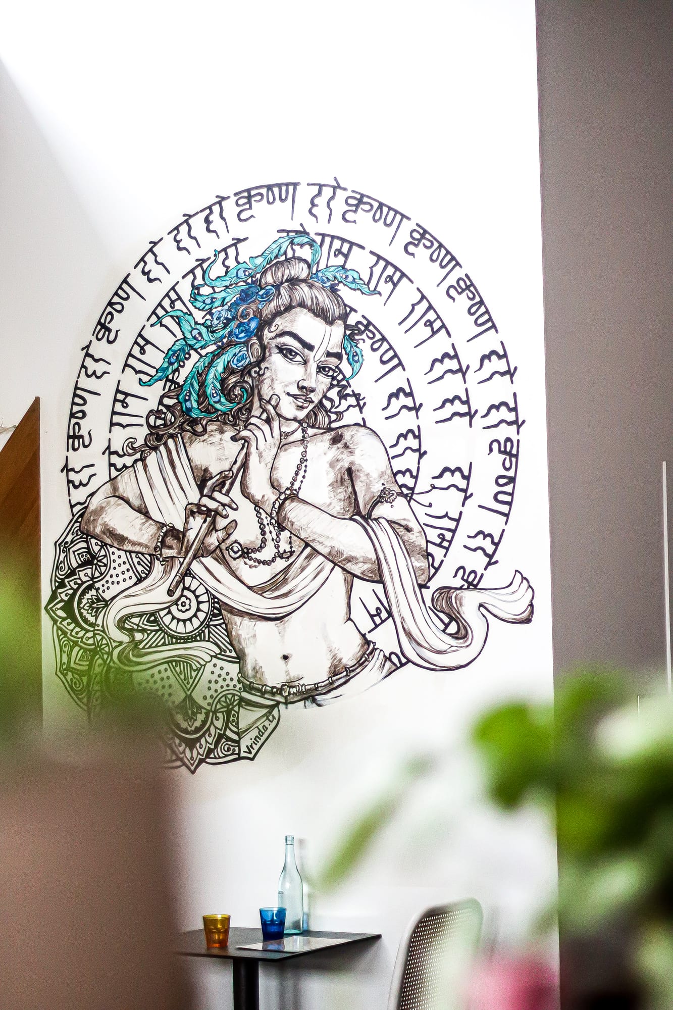 Hand-painted mural of Krishna playing a flute encircled by the Hare Krishna mantra on the wall inside The Cardamom Pod