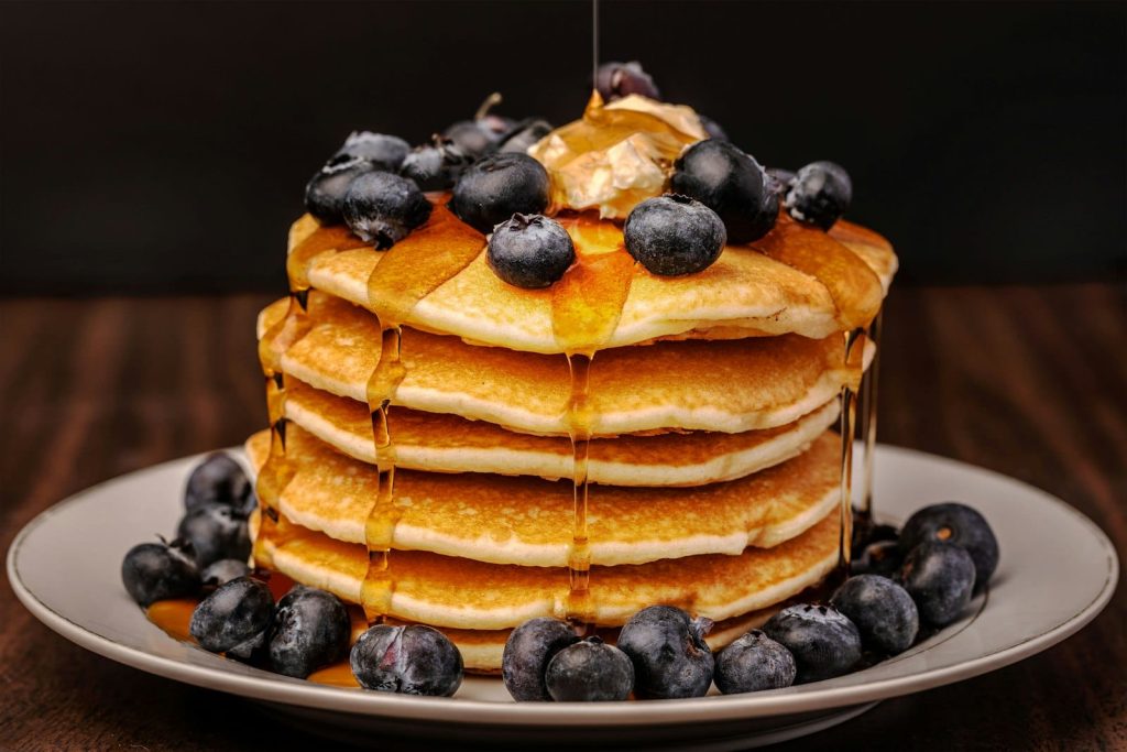 A stack of vegan pancakes with berries and syrup